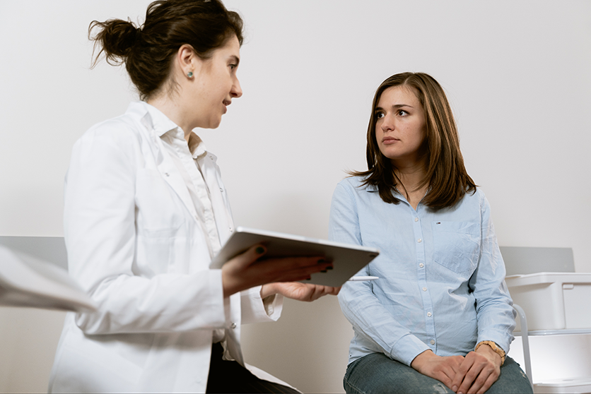 A female doctor explains the risks of a procedure to a female patient so she can make an informed decision.